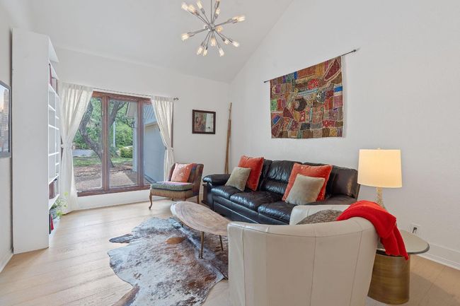 Living room with a chandelier, wood finished floors, and high vaulted ceiling | Image 7