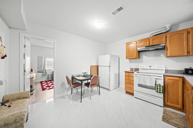 Kitchen with white appliances, baseboards, under cabinet range hood, marble finish floor, and visible vents | Image 19