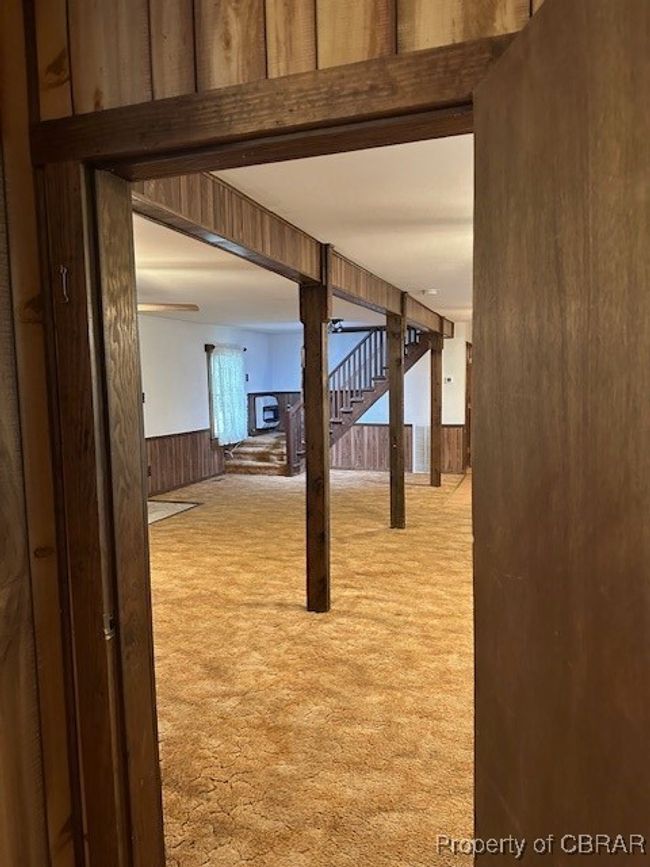 Hall with carpet flooring, wood walls, and a wainscoted wall | Image 11