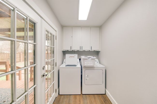 Laundry area with cabinet space, independent washer and dryer, light wood-style flooring, and baseboards | Image 14