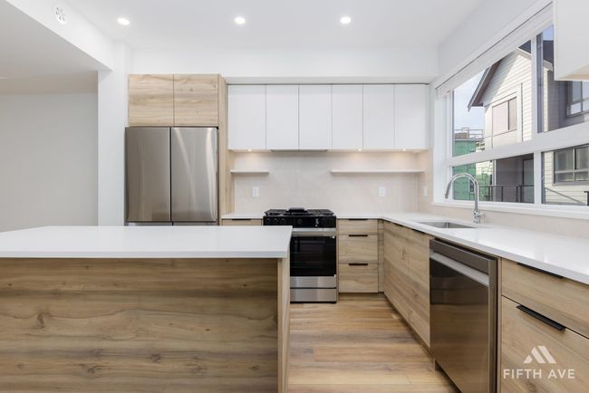 Kitchen with stainless steel appliances, modern cabinets, recessed lighting, light countertops, and white cabinetry | Image 15