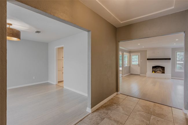 Unfurnished living room featuring plenty of natural light, light wood-style floors, and a fireplace with raised hearth | Image 25