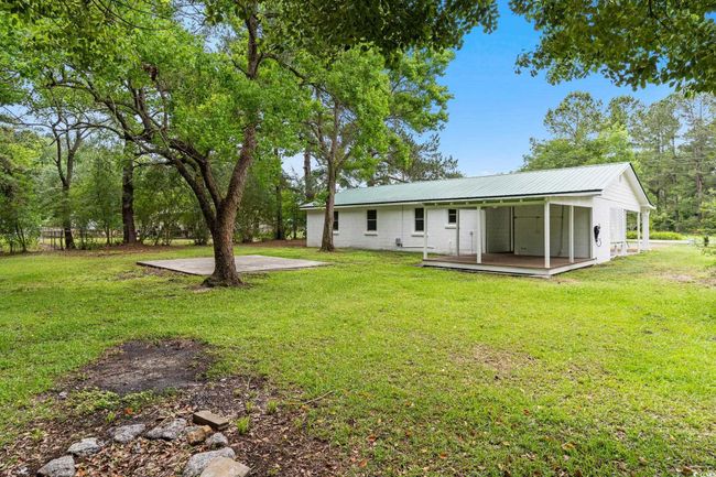 Rear view of property featuring metal roof, a lawn, and a deck | Image 12