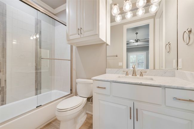 Bathroom with crown molding, combined bath / shower with glass door, vanity, ceiling fan, and toilet | Image 35