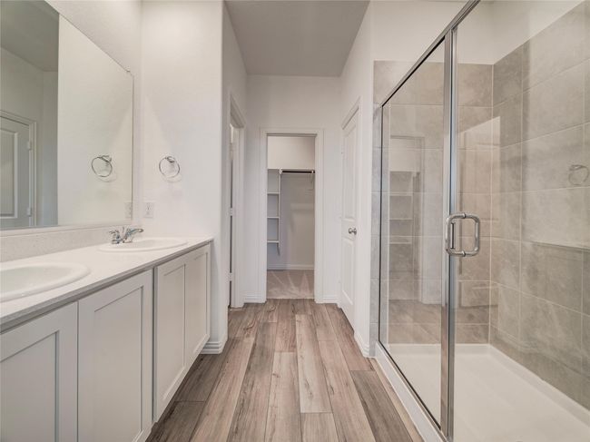 Bathroom featuring a shower stall, double vanity, wood finished floors, and a spacious closet | Image 17