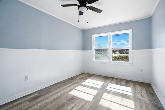 Empty room with wood finished floors, a ceiling fan, and crown molding | Image 18