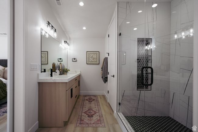 Ensuite bathroom featuring vanity, a stall shower, baseboards, wood finished floors, and recessed lighting | Image 11