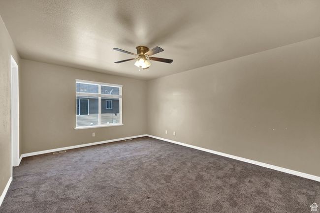 Empty room featuring ceiling fan and dark carpet | Image 11