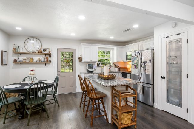 Kitchen with stainless steel appliances, dark wood-type flooring, a kitchen island, light stone counters, and a kitchen breakfast bar | Image 11