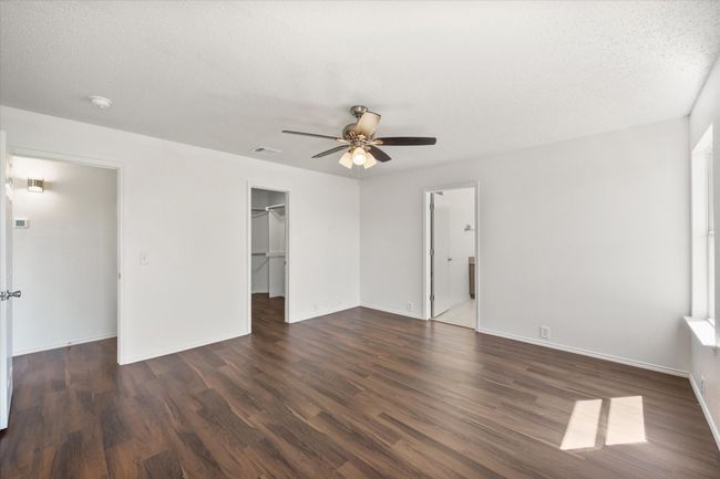 Unfurnished bedroom with wood finished floors, a spacious closet, a closet, and baseboards | Image 13