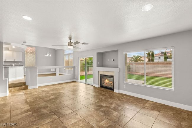 Unfurnished living room featuring a ceiling fan, a textured ceiling, a tiled fireplace, baseboards, and recessed lighting | Image 17