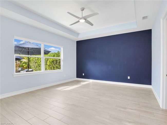 Empty room with light hardwood / wood-style floors, ceiling fan, and a tray ceiling | Image 20