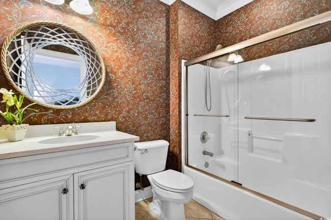 Full bath with wallpapered walls, vanity, bath / shower combo with glass door, and tile patterned floors | Image 30