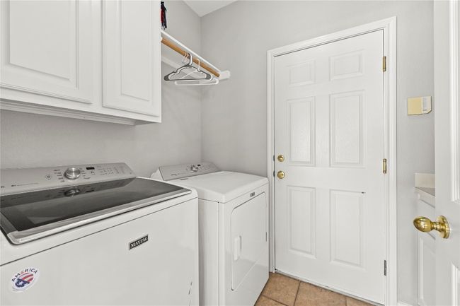Laundry room featuring light tile patterned floors, cabinet space, and washing machine and clothes dryer | Image 20
