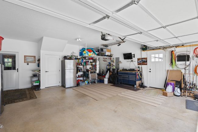 Garage featuring a garage door opener, freestanding refrigerator, and a workshop area | Image 33