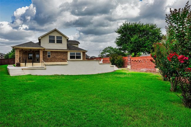 Rear view of house featuring ceiling fan, roof with shingles, and brick siding | Image 5