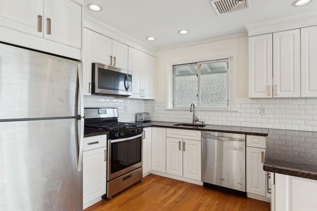 Kitchen featuring white cabinetry, appliances with stainless steel finishes, a sink, and visible vents | Image 10