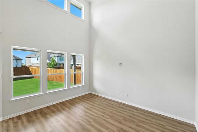 Empty room featuring wood finished floors, plenty of natural light, and a high ceiling | Image 10