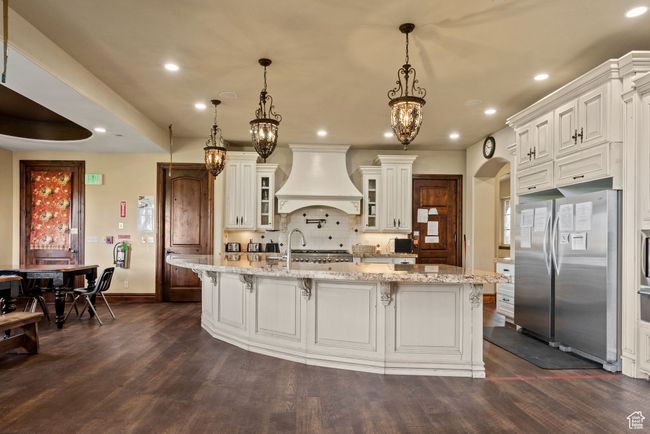 Kitchen featuring custom exhaust hood, baseboards, freestanding refrigerator, and dark wood-type flooring | Image 18