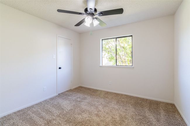 Carpeted empty room featuring baseboards, a textured ceiling, and ceiling fan | Image 17