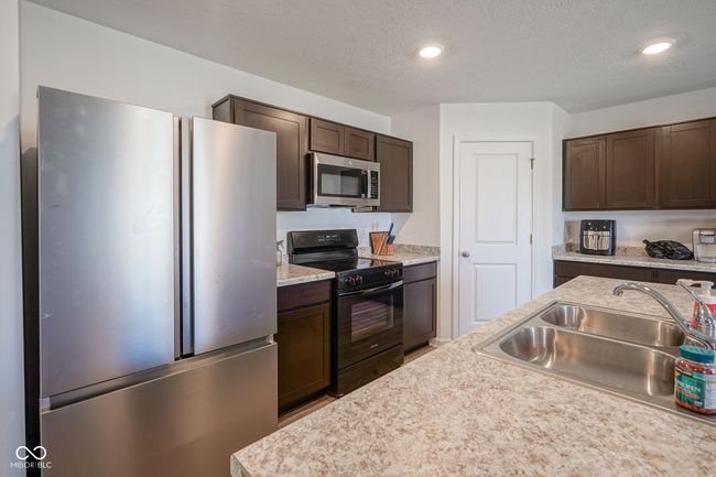 kitchen featuring stainless steel appliances, dark brown cabinets, light countertops, recessed lighting, and a textured ceiling | Image 12