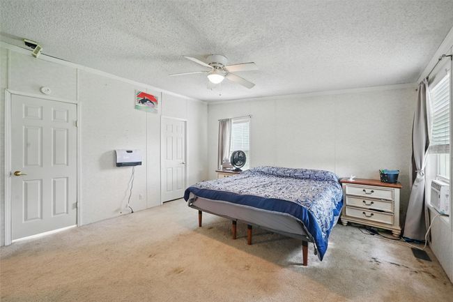 Bedroom featuring carpet flooring, ornamental molding, a textured ceiling, a ceiling fan, and a closet | Image 10