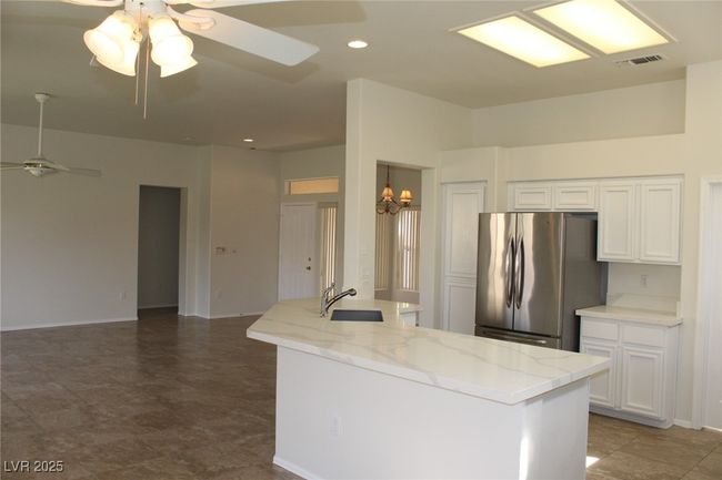 Kitchen with a sink, ceiling fan with notable chandelier, visible vents, and freestanding refrigerator | Image 10