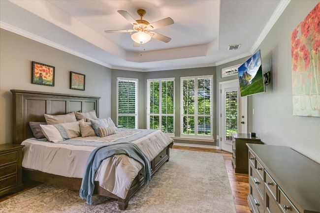 Bedroom featuring a raised ceiling, wood finished floors, access to exterior, ceiling fan, and ornamental molding | Image 4