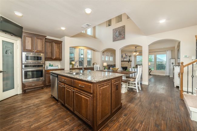 Kitchen with appliances with stainless steel finishes, a sink, light stone countertops, dark wood finished floors, and healthy amount of natural light | Image 6