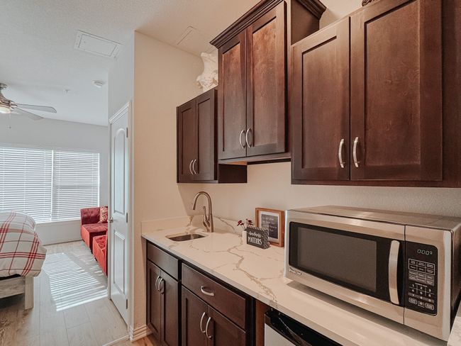Kitchenette located in lockout bedroom featuring dark brown cabinetry, stainless steel microwave, updated counters , and a sink. | Image 21
