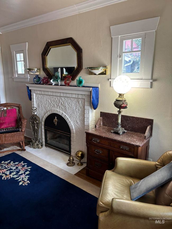 Living area with plenty of natural light, crown molding, wood finished floors, and a fireplace with flush hearth | Image 7