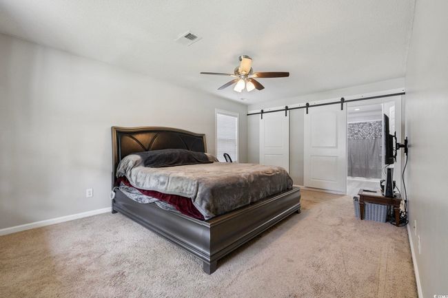 Bedroom featuring carpet floors, baseboards, a ceiling fan, and a barn door | Image 17