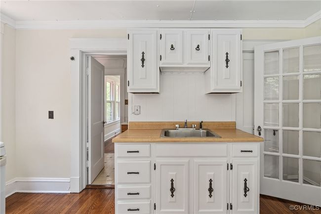 Kitchen with a sink, white cabinets, light countertops, wood flooring, and crown molding | Image 41