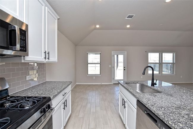 Kitchen with a sink, plenty of natural light, appliances with stainless steel finishes, decorative backsplash, and vaulted ceiling | Image 12