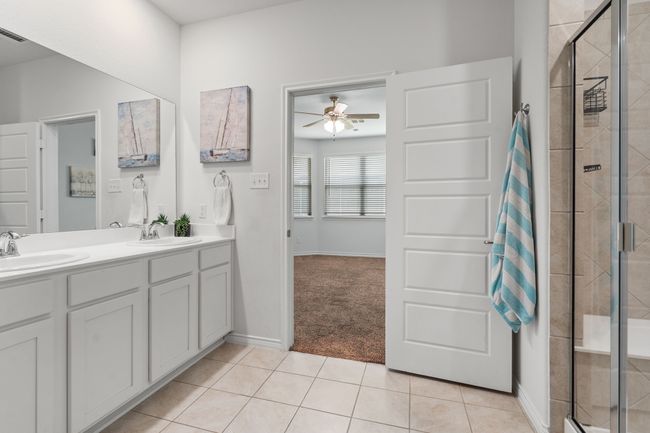 Spacious Primary Bathroom with double Vanity, shower with built in bench seat, lighting, tile patterned floors, private toilet room, Linen/Towel Shelves, and Walk in Closet | Image 19