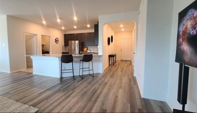 Kitchen with freestanding refrigerator, light wood finished floors, arched walkways, light countertops, and dark brown cabinetry | Image 4