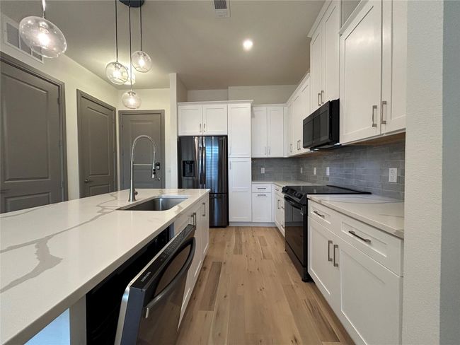 Kitchen with white cabinets, sink, and black appliances | Image 8