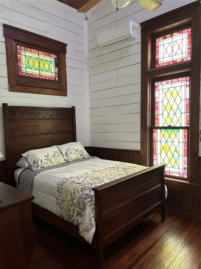 Bedroom with wood walls, wood finished floors, and a wall unit AC | Image 20