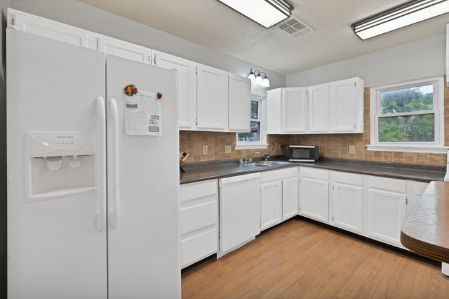 Kitchen featuring upgraded lighting, dark countertops, white cabinets, and white appliances | Image 16