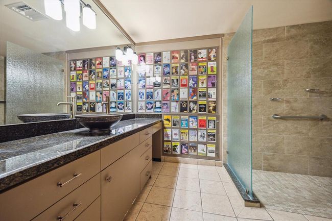 The primary bath boasts a granite countertop, a vessel sink, vanity space, and a stunning walk-in shower. | Image 19