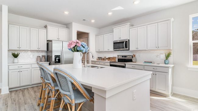 Kitchen featuring appliances with stainless steel finishes, a sink, light wood-style flooring, a kitchen island with sink, and recessed lighting | Image 11