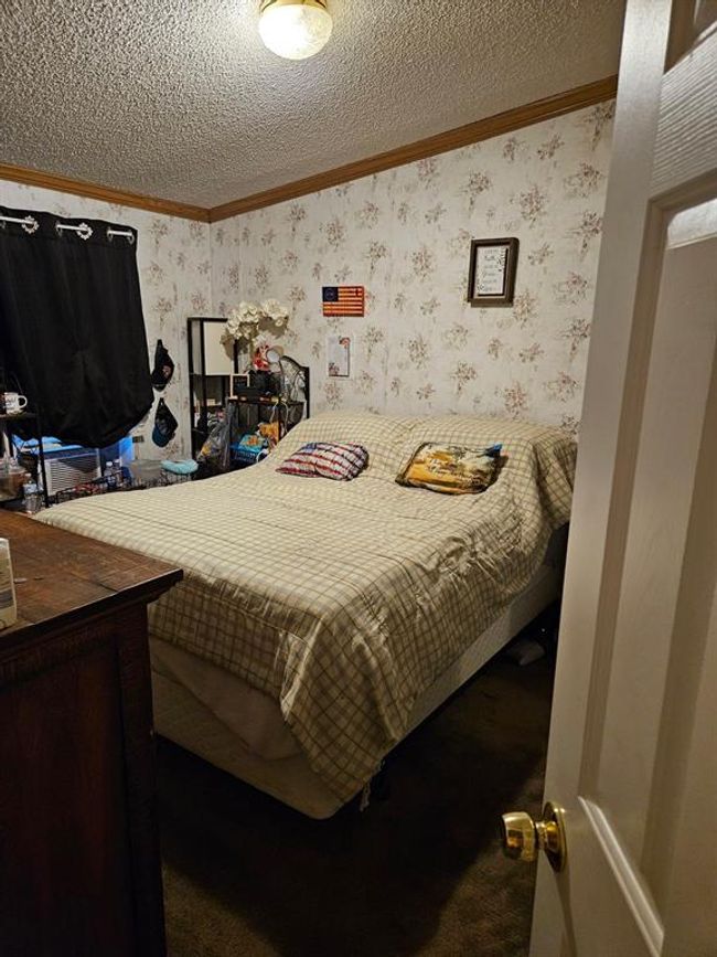 Bedroom featuring crown molding, dark colored carpet, and a textured ceiling | Image 33