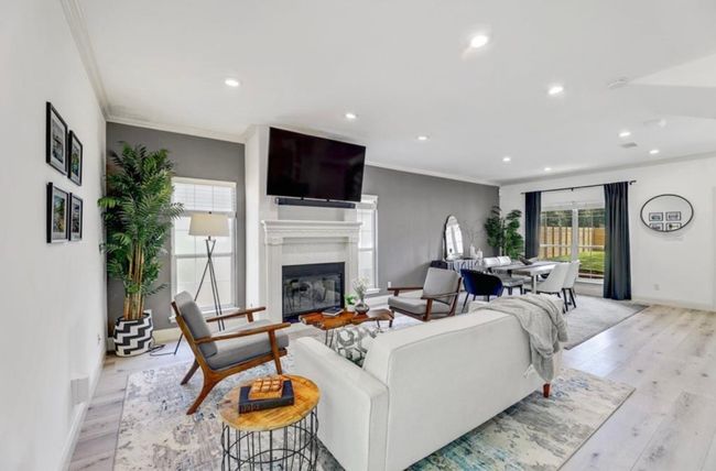 Living room with recessed lighting, ornamental molding, baseboards, light wood-style flooring, and a glass covered fireplace | Image 11