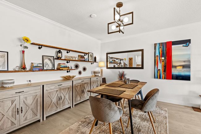 Dining space with a notable chandelier, light wood-style floors, ornamental molding, and a textured ceiling | Image 7