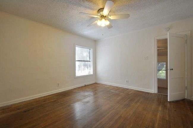 Empty room with wood-type flooring, a textured ceiling, and ceiling fan | Image 6