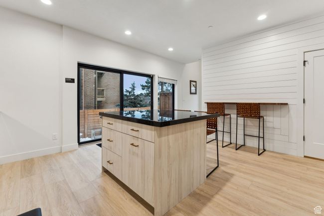 Kitchen featuring light hardwood / wood-style flooring, light brown cabinets, a breakfast bar, and a center island | Image 11