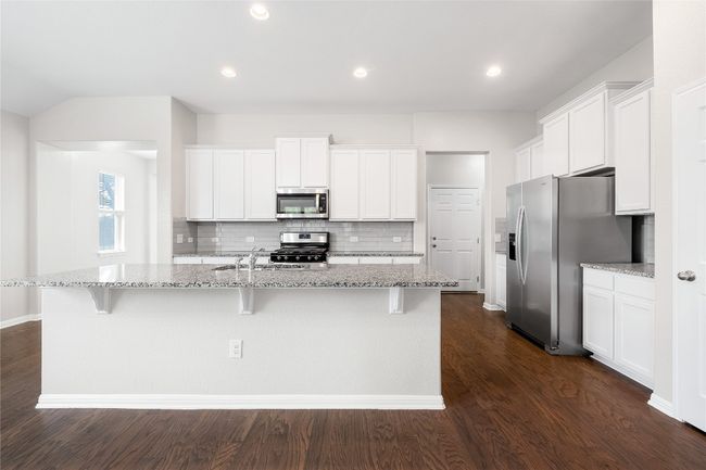 Kitchen with appliances with stainless steel finishes, decorative backsplash, white cabinets, a breakfast bar area, and recessed lighting | Image 17