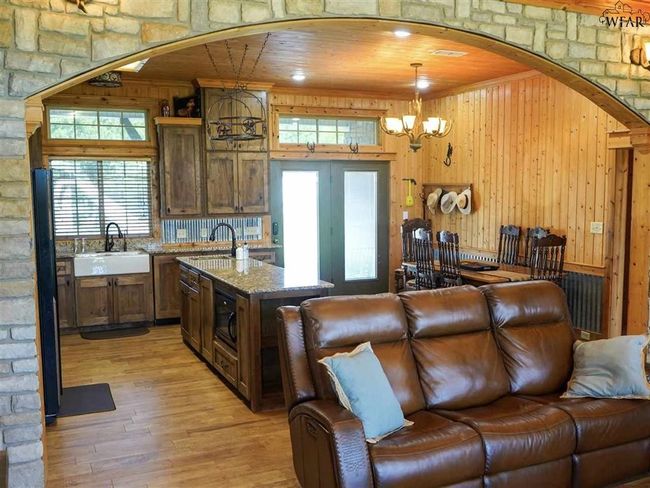 Kitchen featuring sink, hanging light fixtures, light hardwood / wood-style floors, and wood walls | Image 5