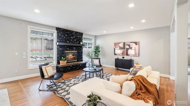 This inviting main living room centers around a striking black stone fireplace, creating a cozy statement feature that contrasts beautifully with the natural light and soft-toned finishes—ready to be styled with your personal touch | Image 16