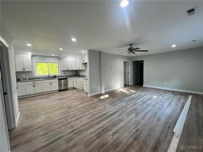 Kitchen featuring ceiling fan, light hardwood / wood-style flooring, stainless steel dishwasher, and white cabinets | Image 3